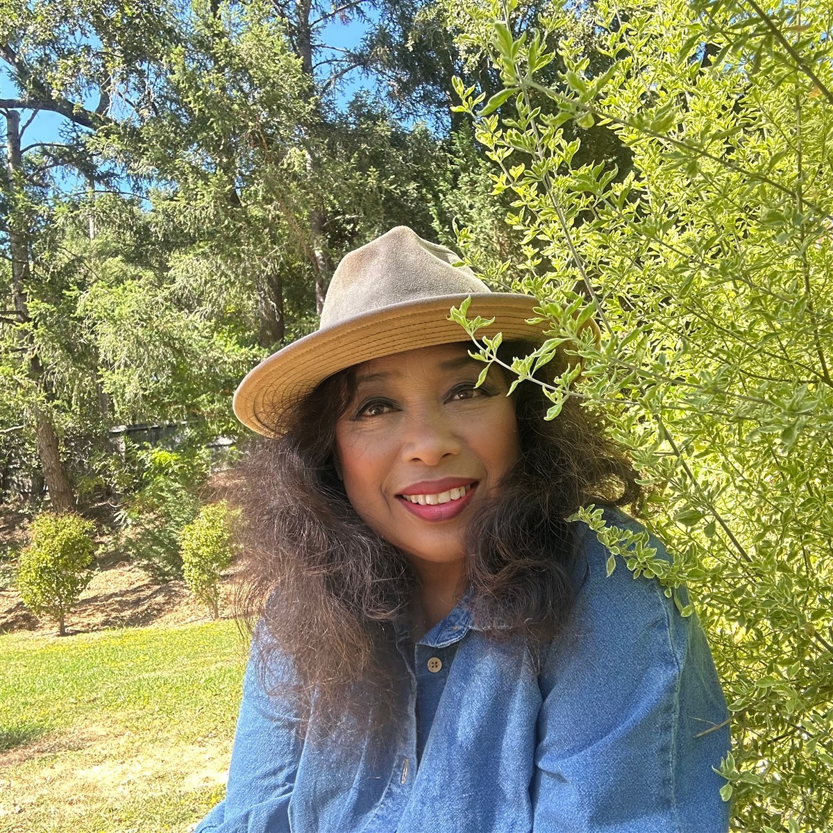 Michellar, Michelle Bond, wearing a wide-brimmed hat among trees